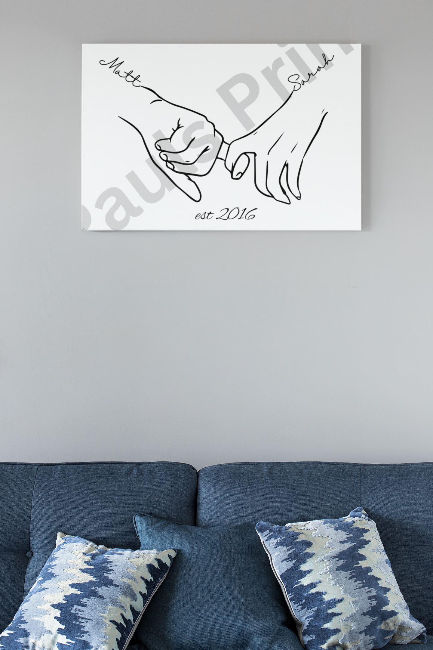 Personalised love line drawing of Matt and Sarah holding hands, est. 2016, in a clean white print above a blue sofa with patterned cushions