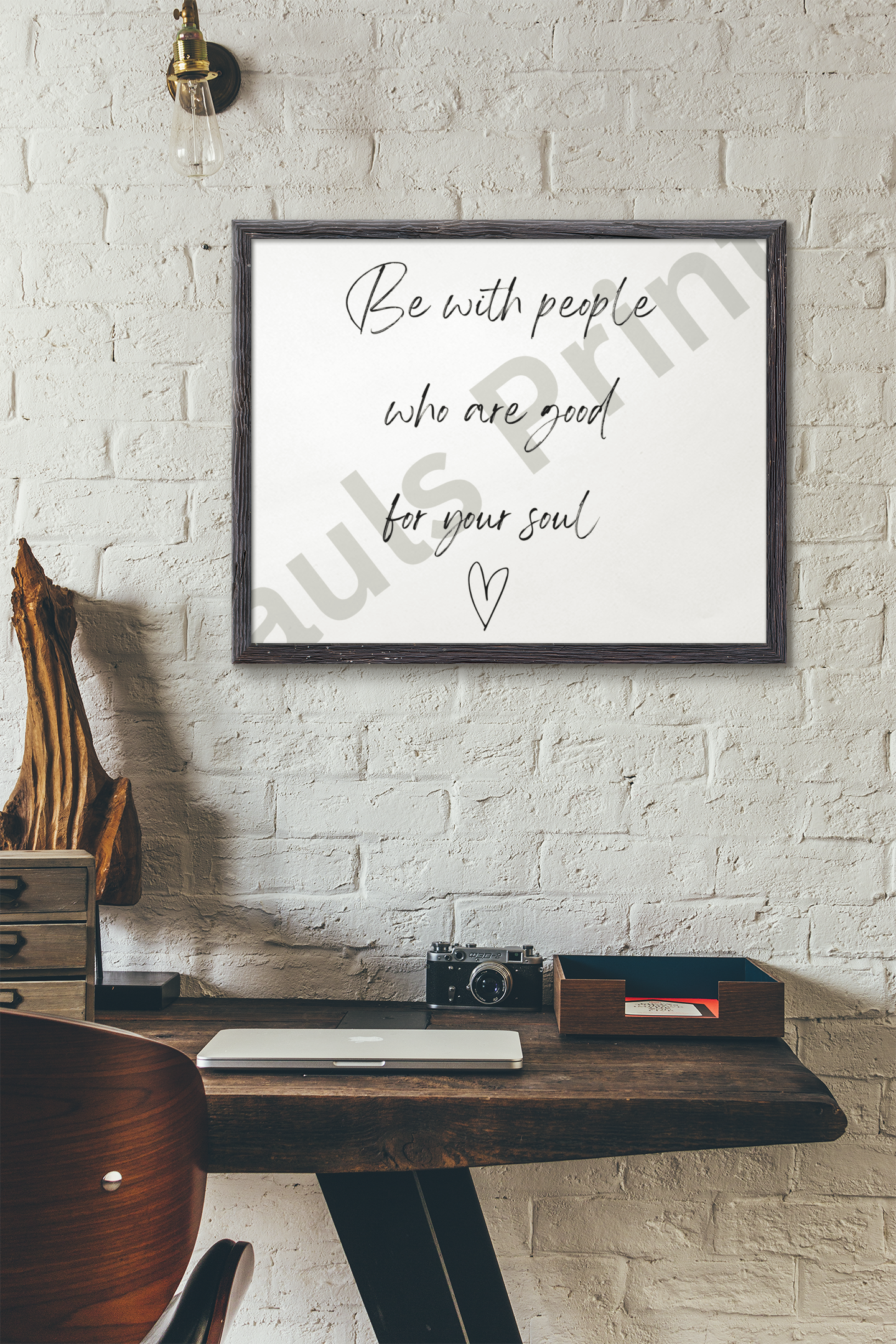 Handwritten quote in a black frame mounted above a rustic desk with vintage decor and an Edison bulb.