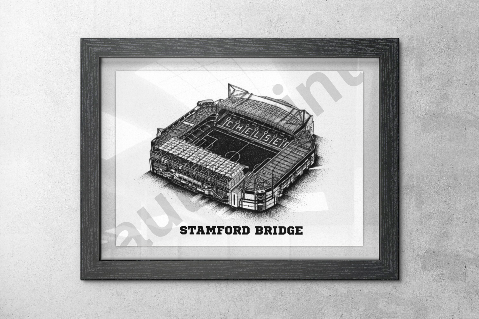 Close-up view of Stamford Bridge football stadium print in a dark wood frame mounted on a textured concrete wall.