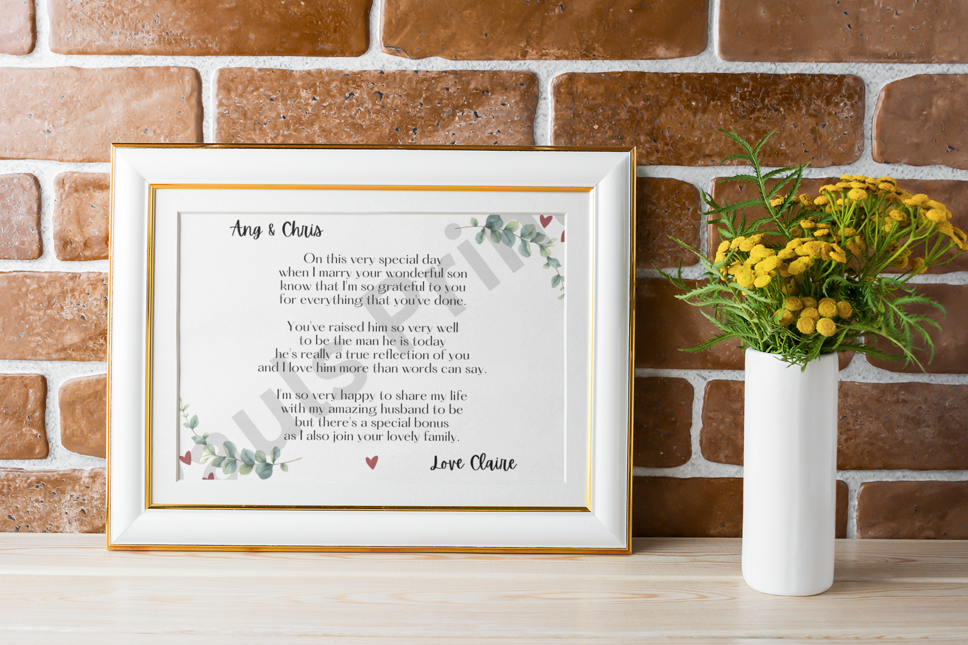 Gold-trimmed white frame holding wedding poem print placed against a rustic brick wall beside a white vase with yellow flowers