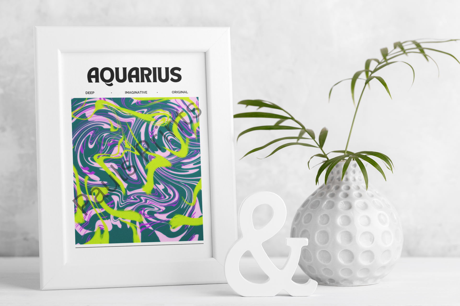 Aquarius star sign artwork in bold abstract colours, framed in white and displayed next to a dotted vase with greenery and a decorative ampersand ornament.