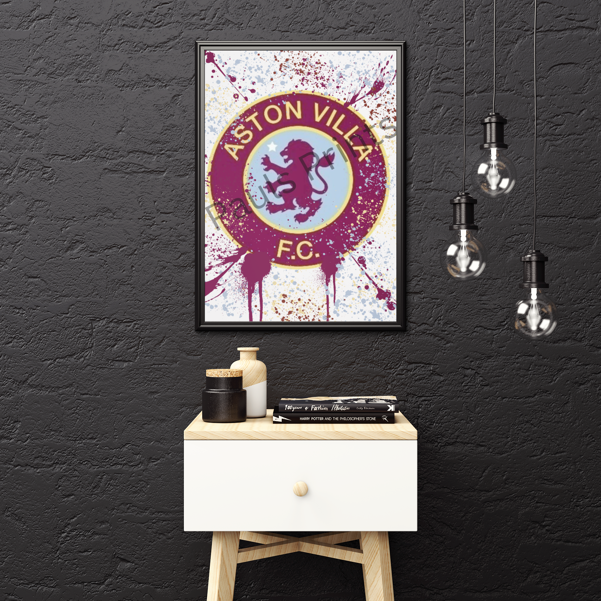 Framed Aston Villa FC splatter-style print displayed on black wall above minimalist side table and hanging light bulbs.
