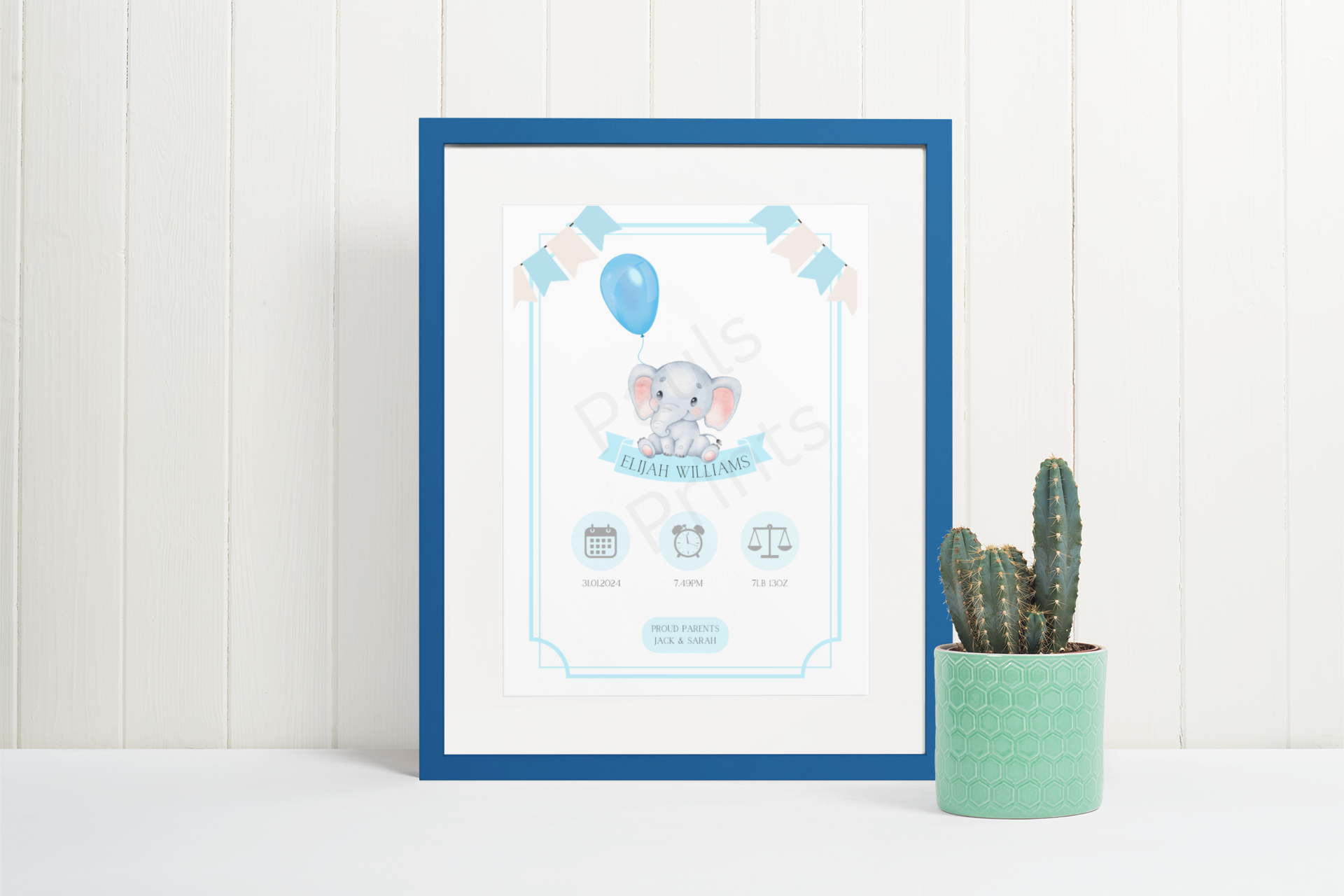 Blue framed baby elephant print with birth info, styled next to a cactus on a white wooden background.