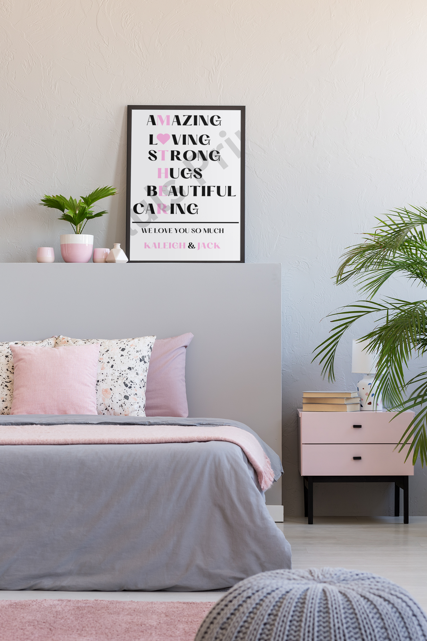 Framed typography print for mothers with words like loving and caring, leaning against a pink and grey bedroom wall near potted plants.