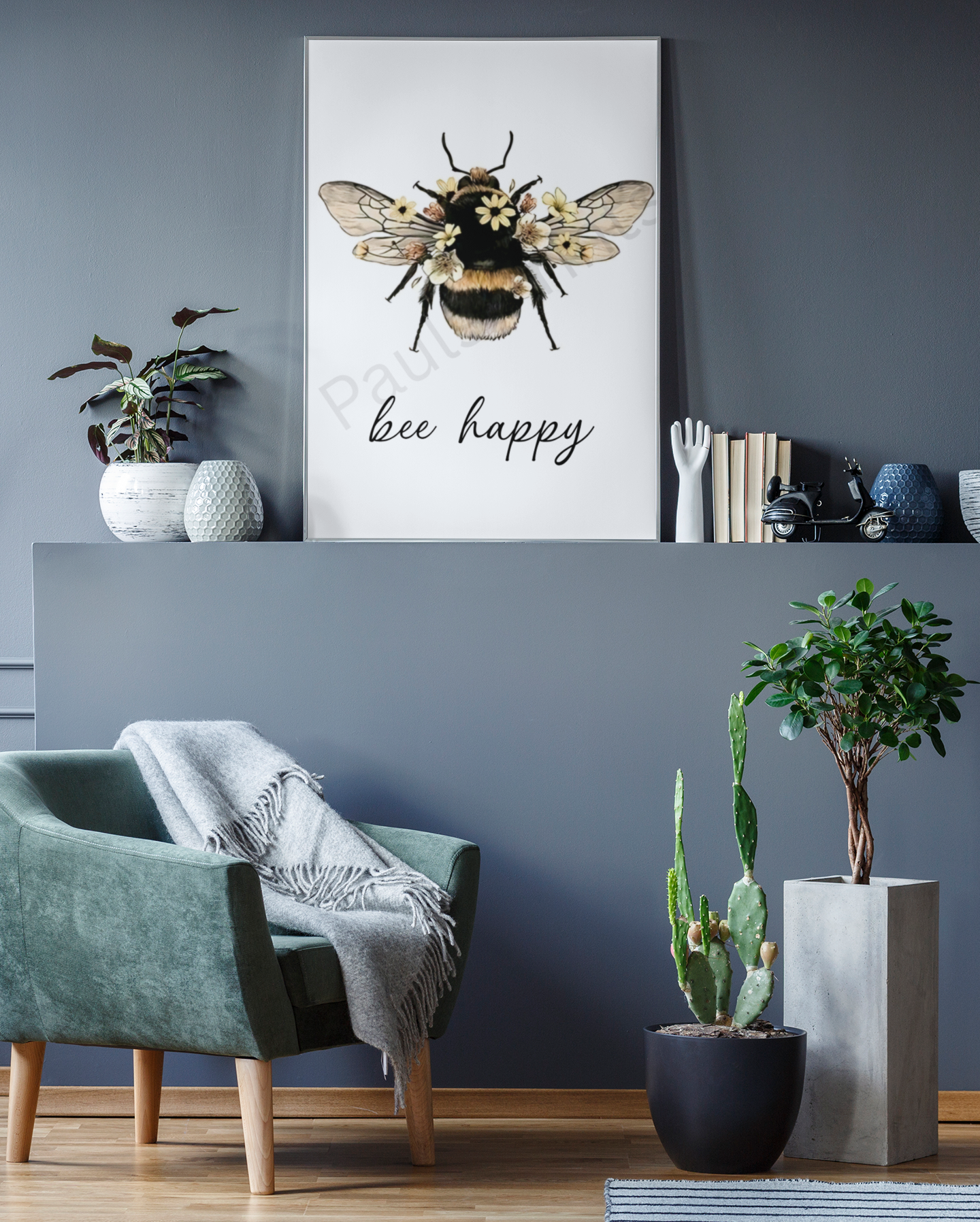 Stylish “bee happy” wall art with a floral bee design, displayed in a modern living room with grey walls, plants, and green armchair.