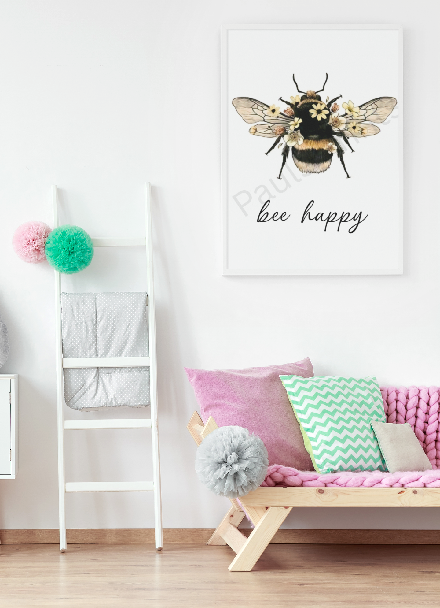 Playful “bee happy” wall art with bee and floral details, hanging in a children’s room with pastel cushions and pom-pom ladder decor.