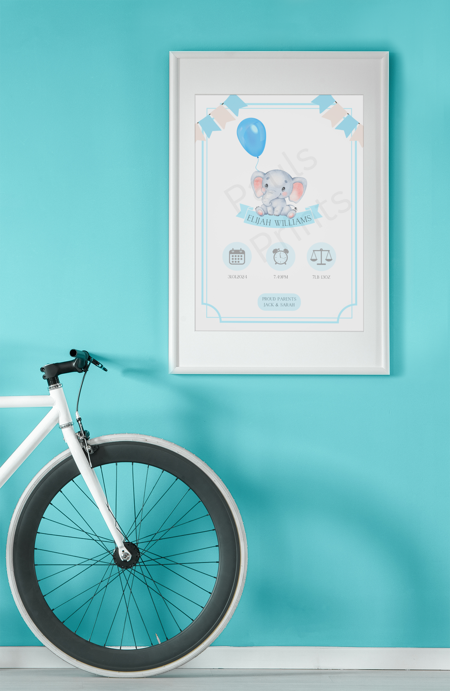 Framed baby birth print with blue elephant, styled on a turquoise wall next to a white bicycle wheel.