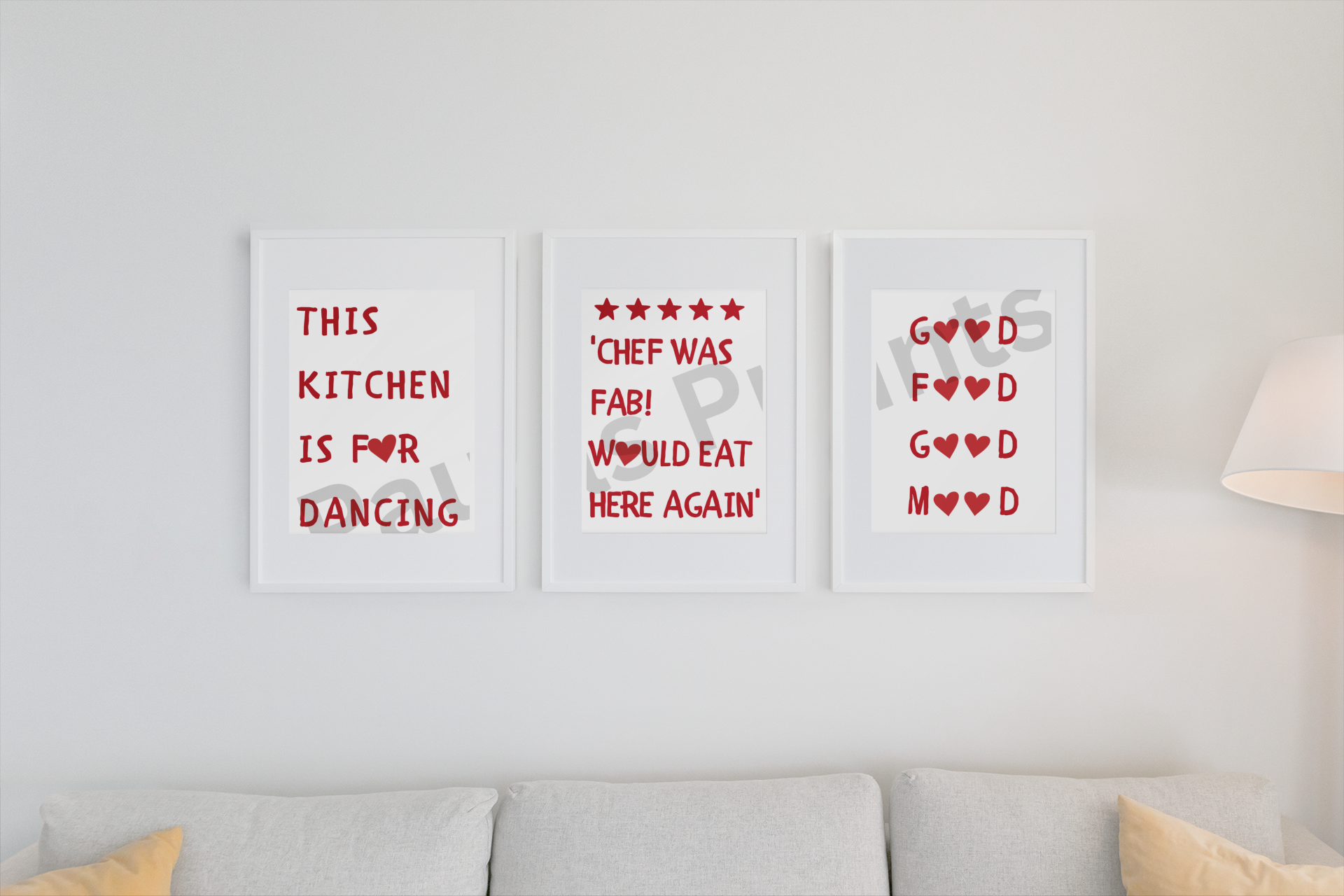 Playful kitchen wall art set in white frames with red lettering and heart accents, arranged above a light grey sofa.
