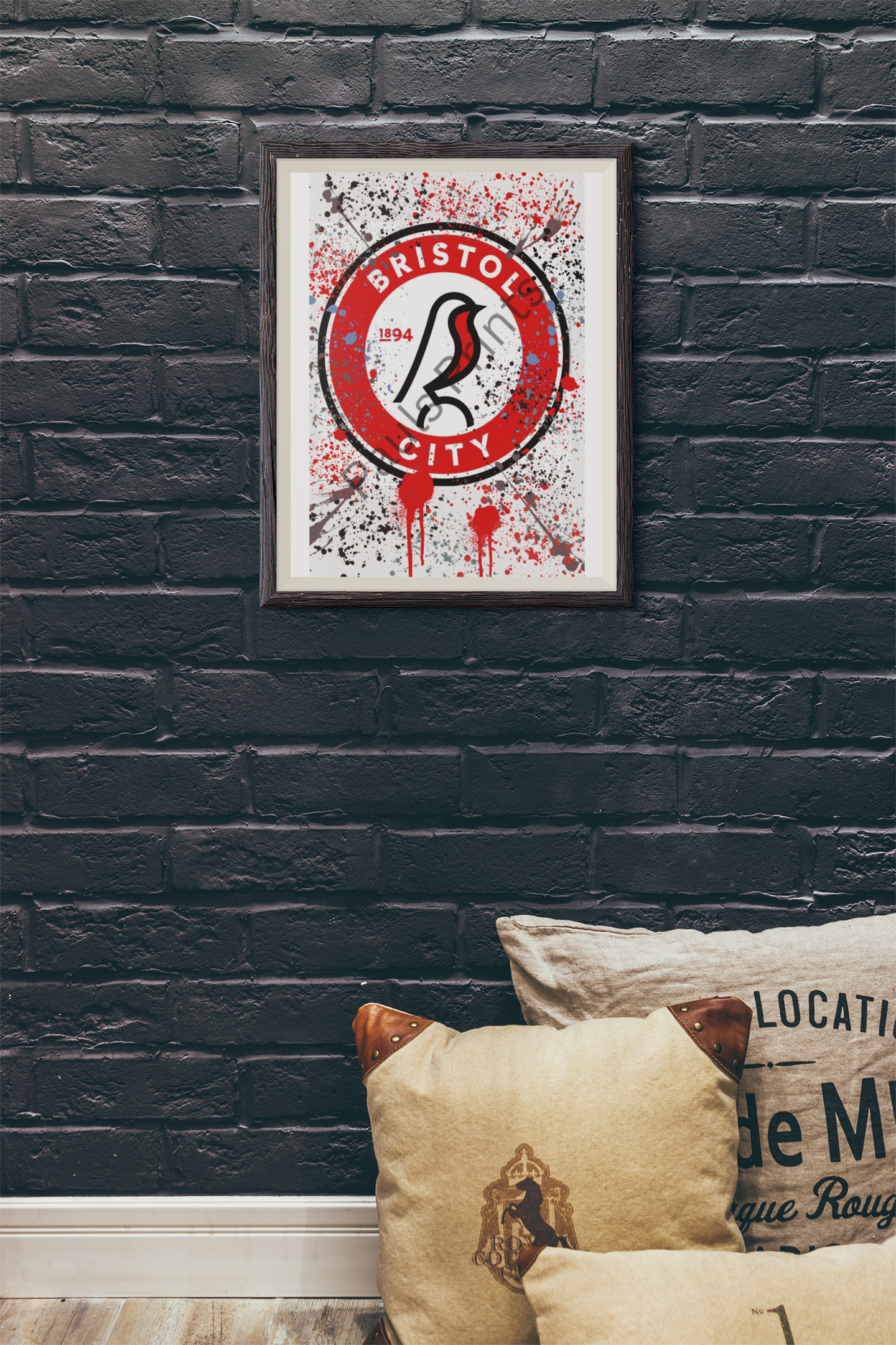 Bristol City FC graffiti-effect wall art in a dark wooden frame against a black painted brick wall, with vintage cushions on the floor.