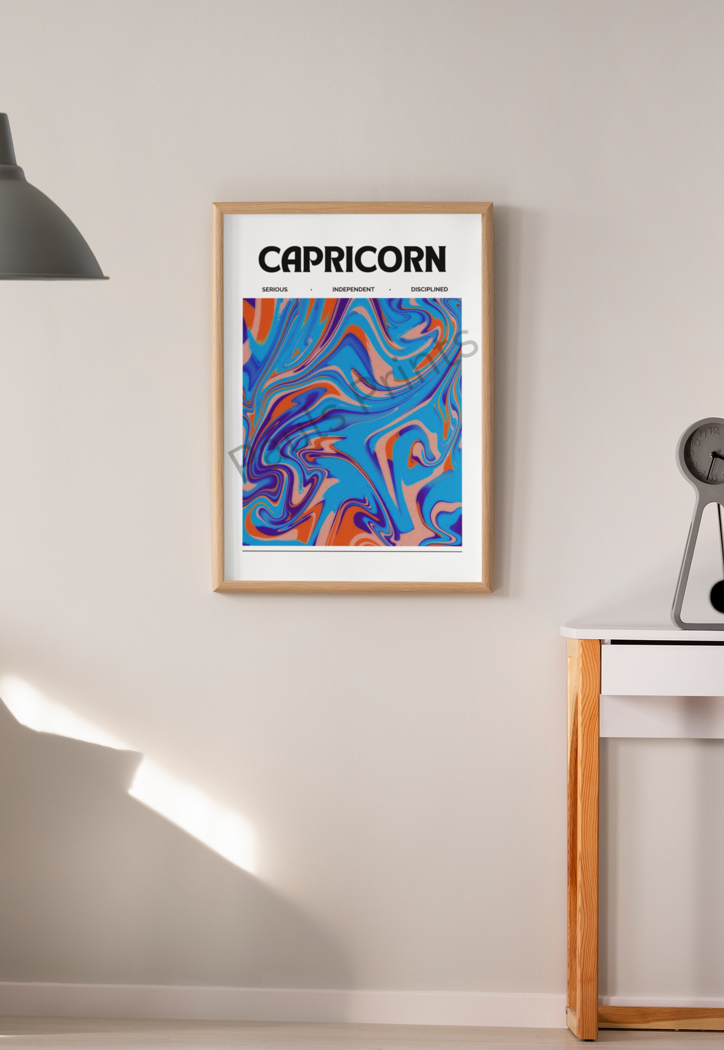 Abstract Capricorn star sign print in vibrant blues and oranges, displayed in a natural wood frame on a beige wall beside a modern desk.