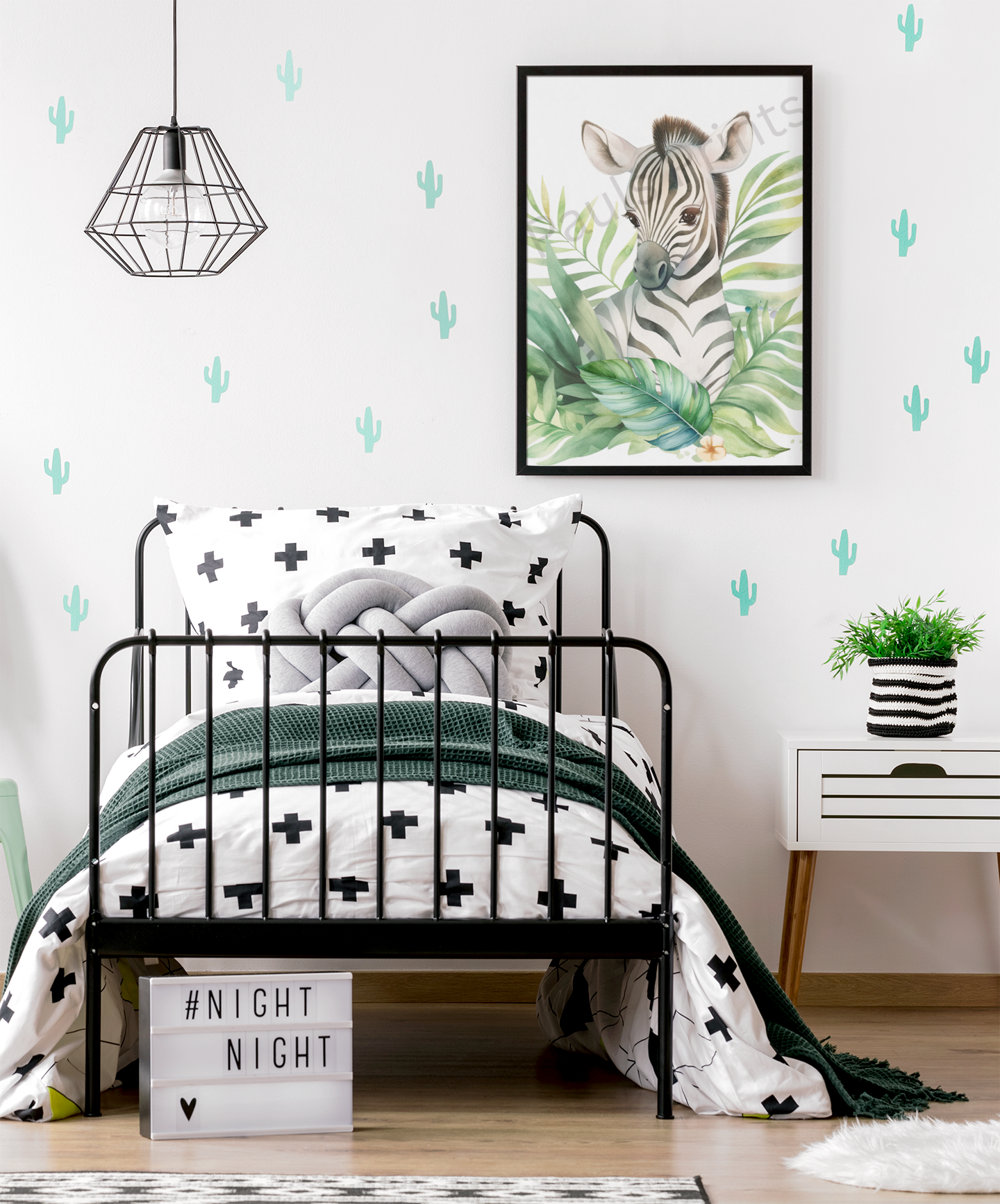 Adorable zebra print in a black frame, set against a white wall with mint cactus decals above a monochrome kids’ bed with black cross duvet.