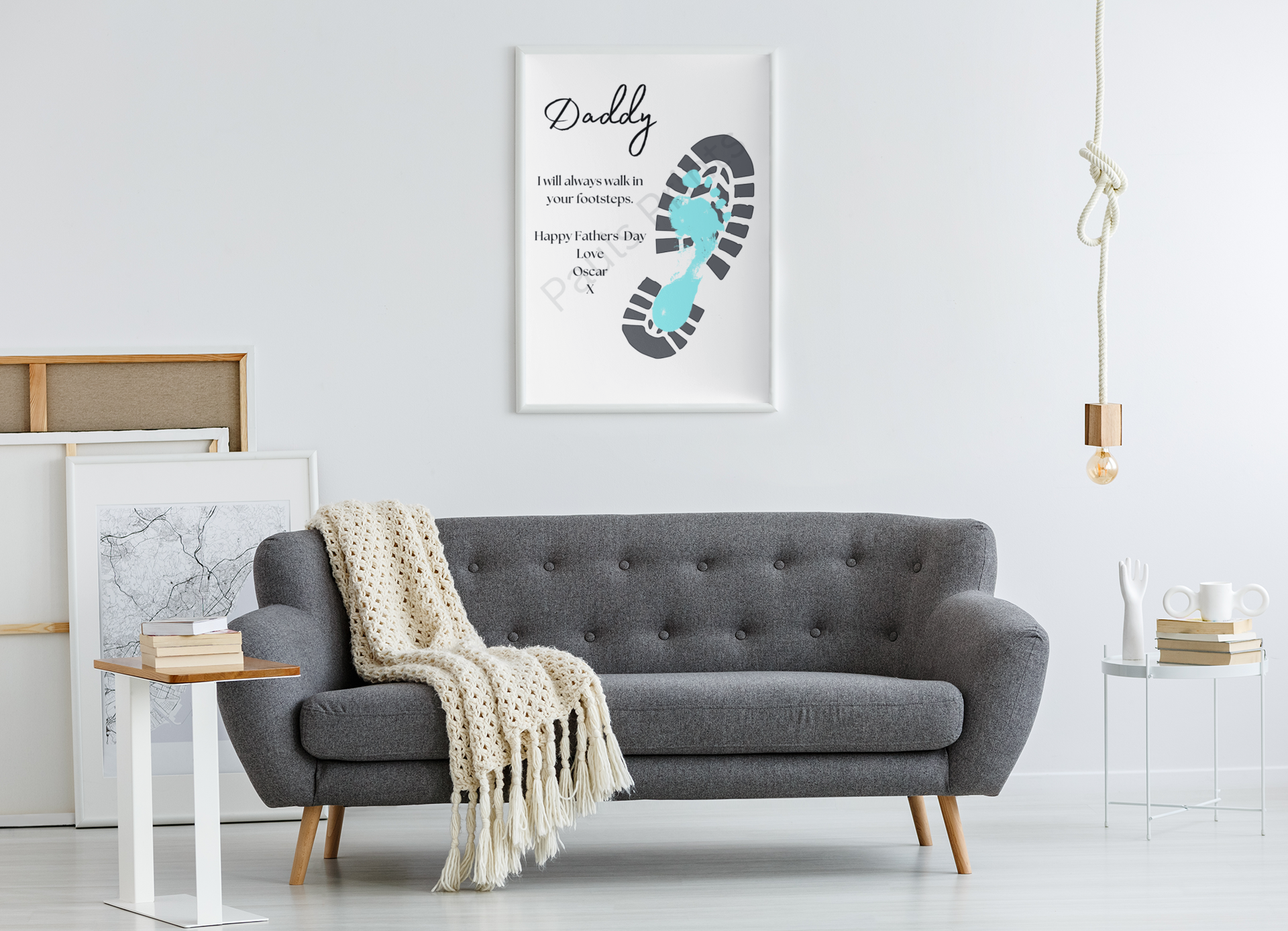 Large framed footprint artwork with light blue foot and boot print hanging above grey sofa in minimalist living space.