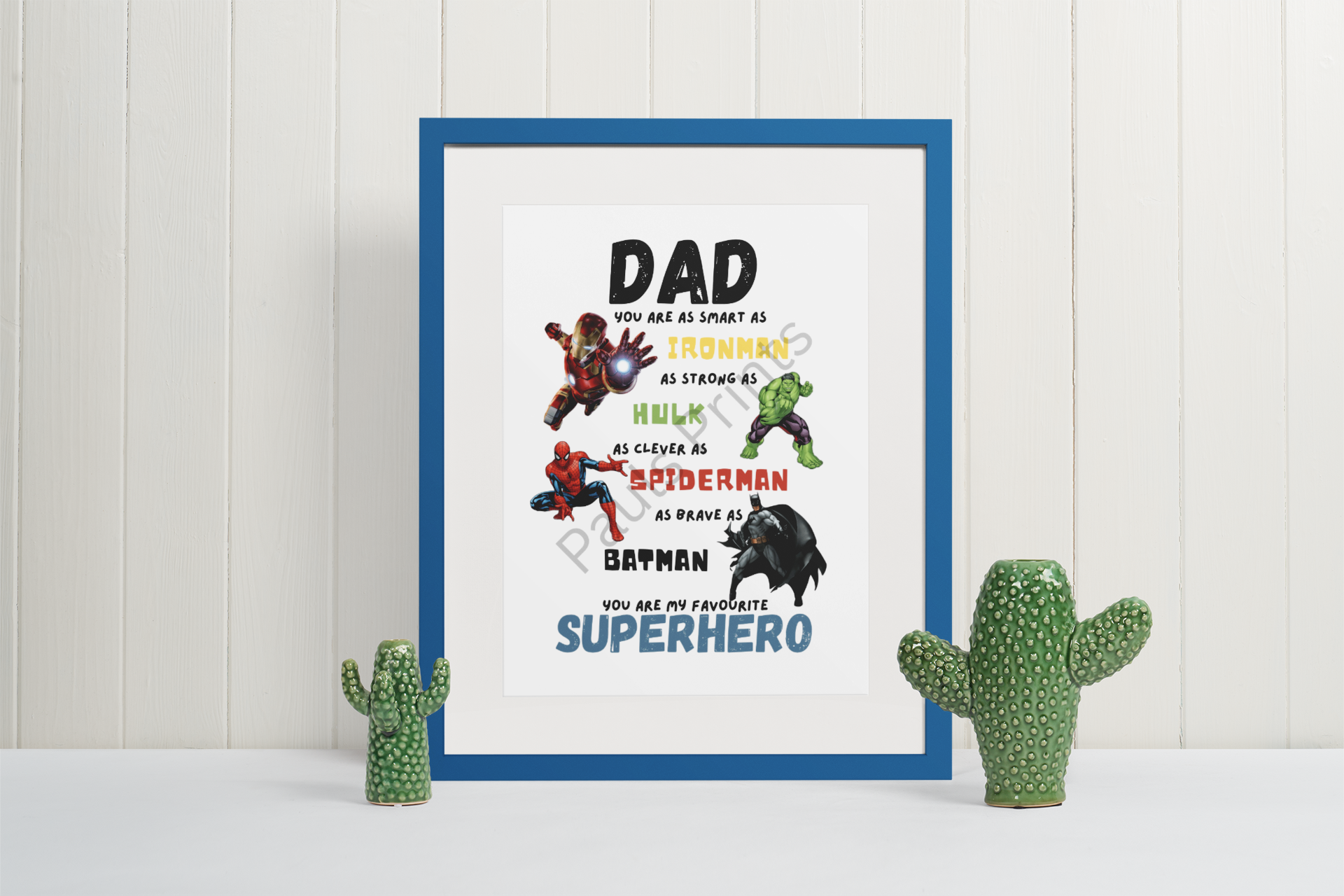 Vibrant superhero quote print for dad with comic characters, set in blue frame with ceramic cactus decorations.