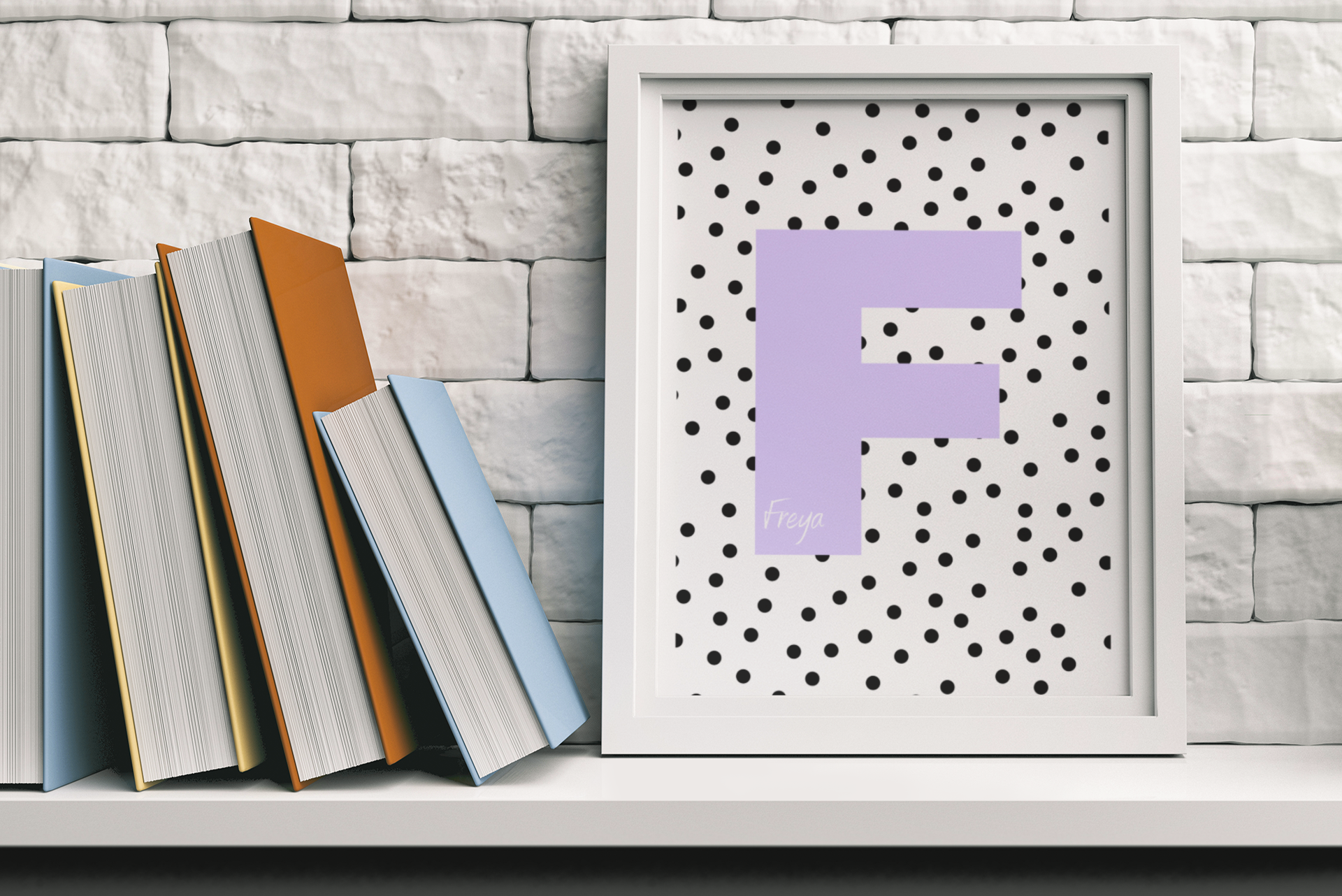 White-framed letter F print in lavender with black polka dots, leaning against white brick wall beside stack of colorful books.