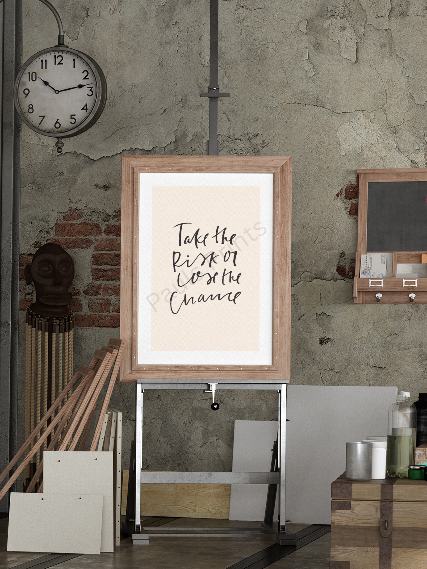 Rustic industrial setting with framed print reading “Take the risk or lose the chance” in black handwritten script on beige background, placed on an easel in front of a textured wall.