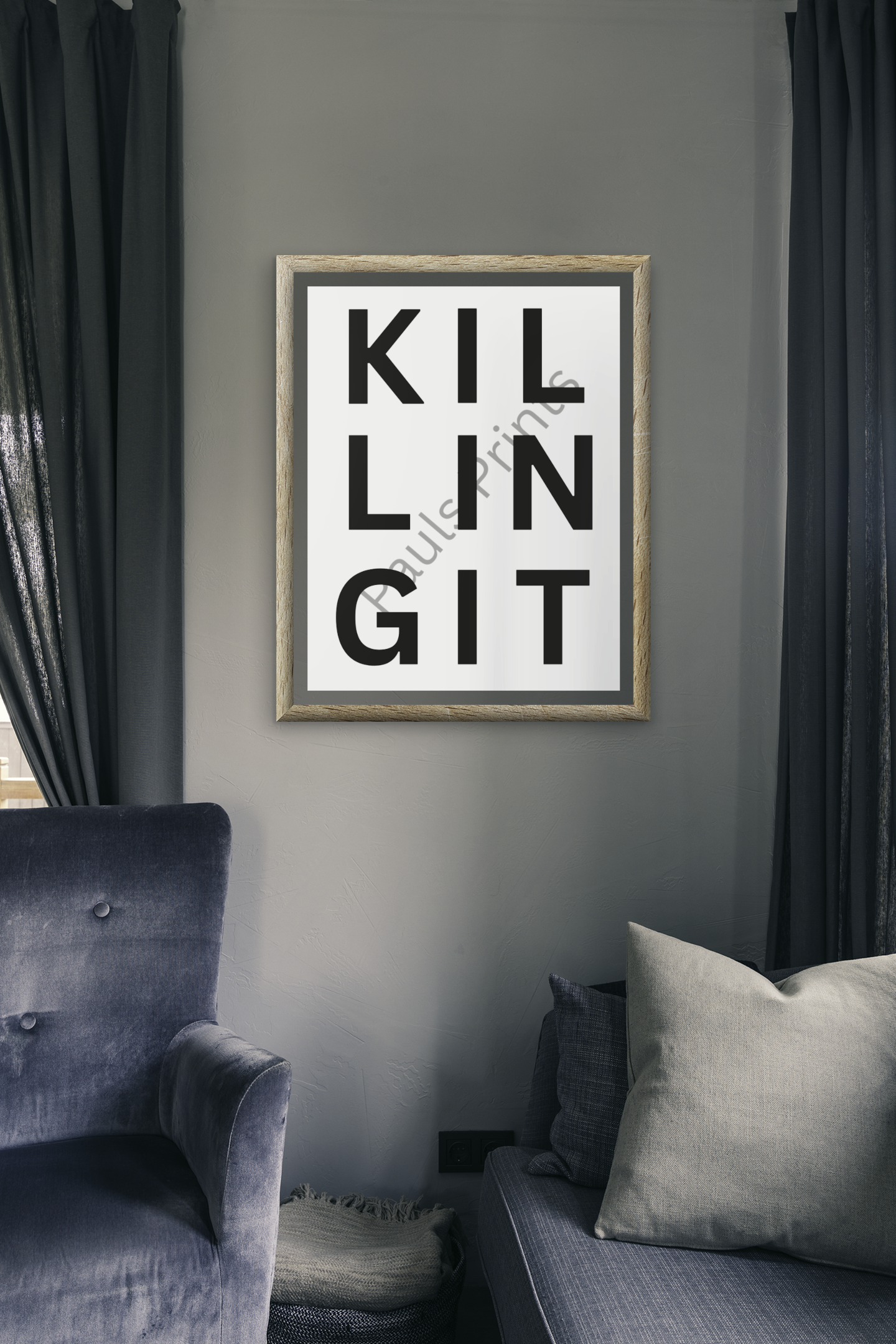 Bold “Killing It” framed print hanging on a grey wall between dark curtains and grey seating in a contemporary living space.