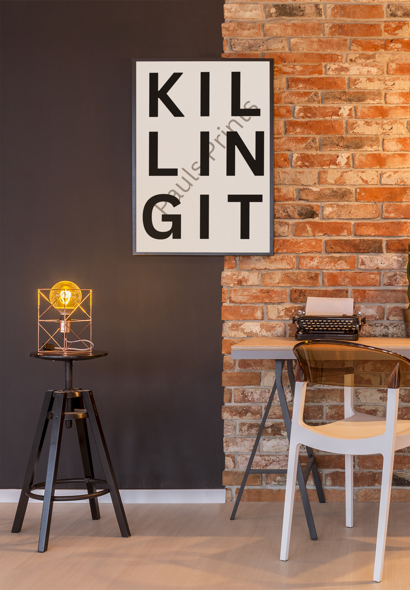 Monochrome “Killing It” quote print displayed against a split black and brick wall backdrop in an industrial-style workspace.