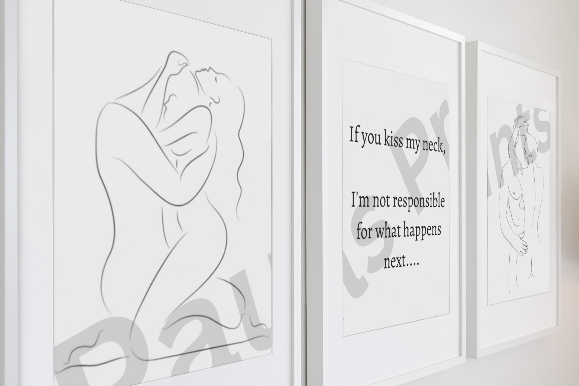 A close-up side perspective of three white-framed prints — two sensual line drawings and a bold typographic statement — offering a clean and modern detail shot.