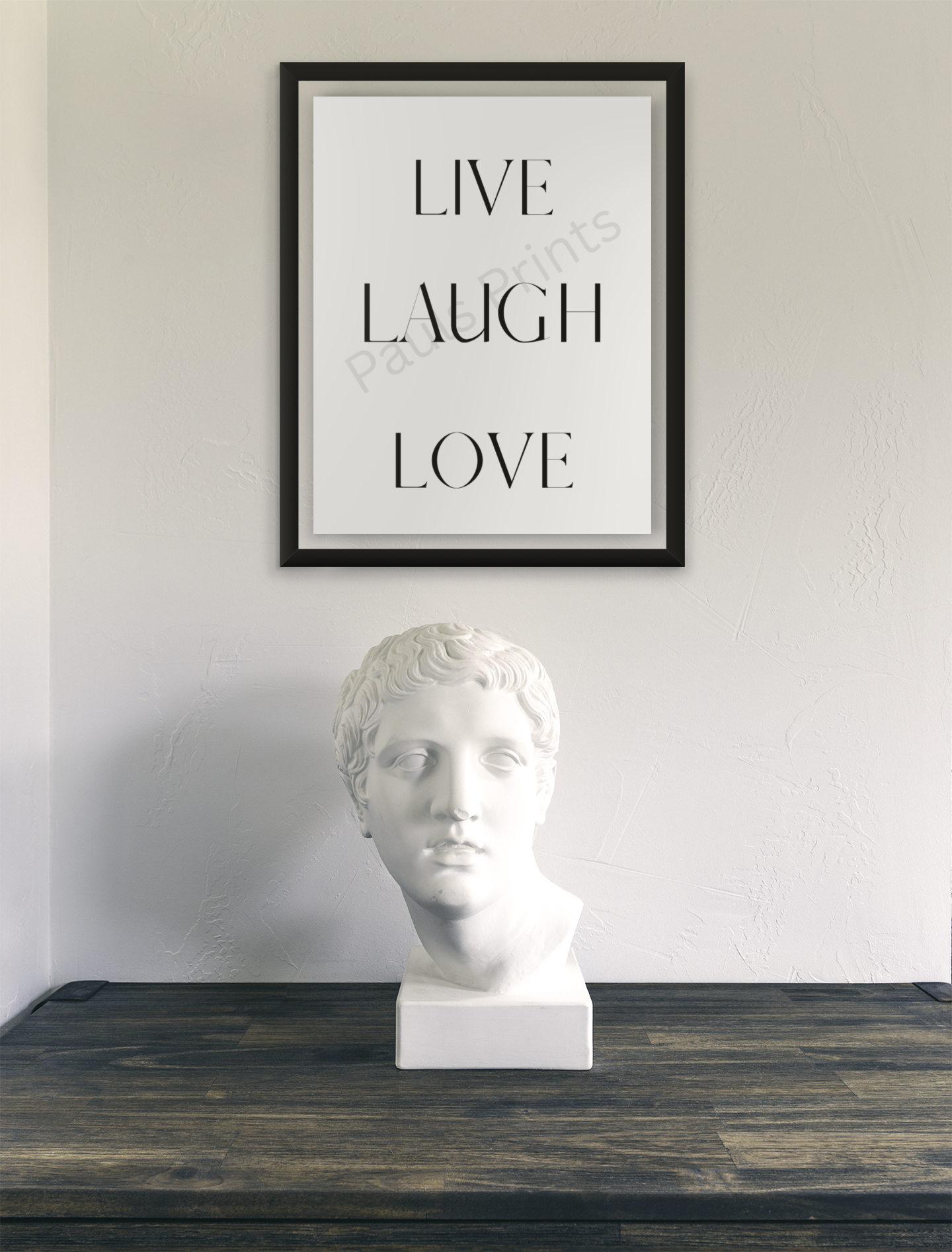 Black-framed Live Laugh Love print above a wooden surface with a classical white bust sculpture.