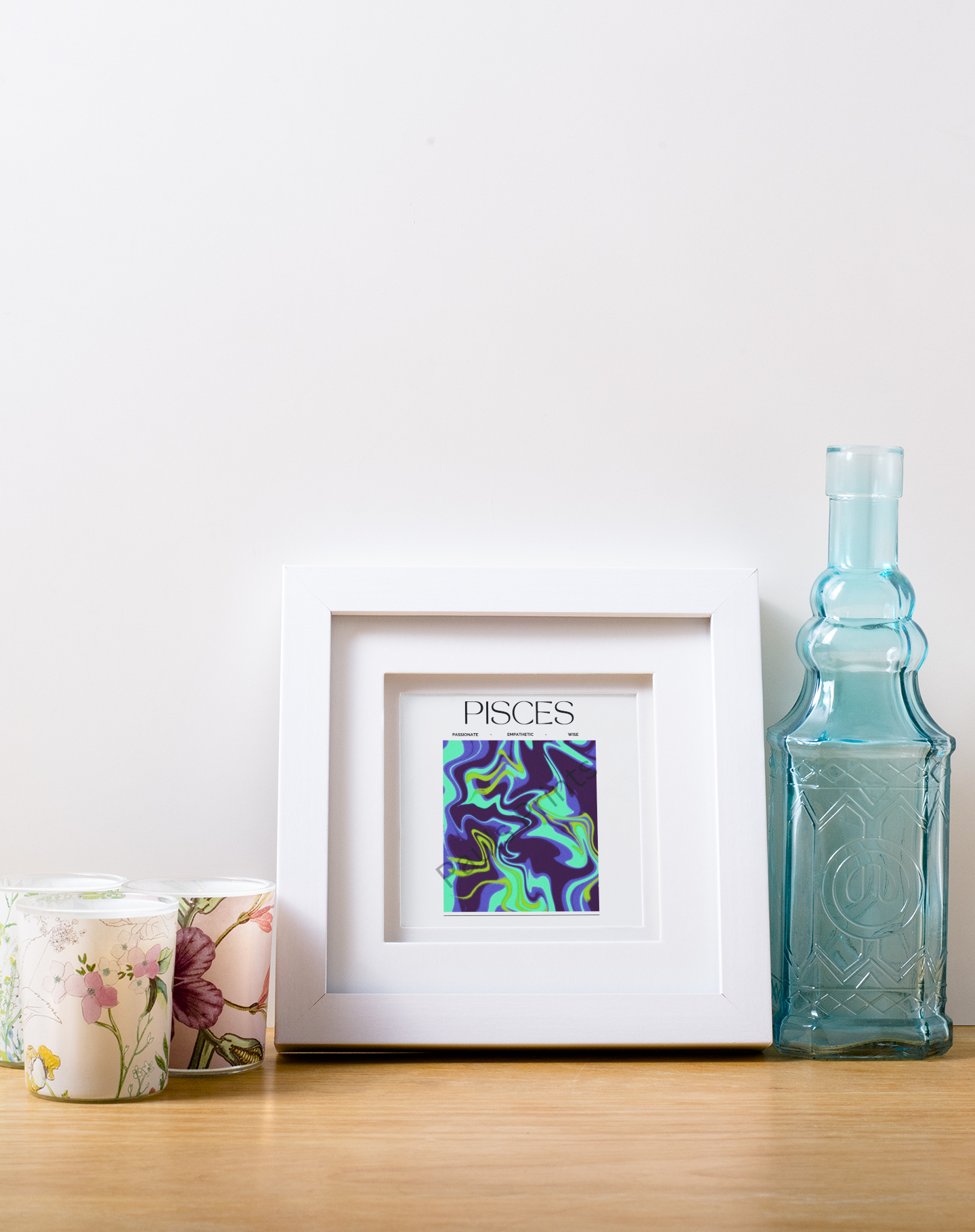 Small square Pisces print with vibrant purple and teal swirls, placed in a white frame alongside floral candles and a blue decorative bottle.