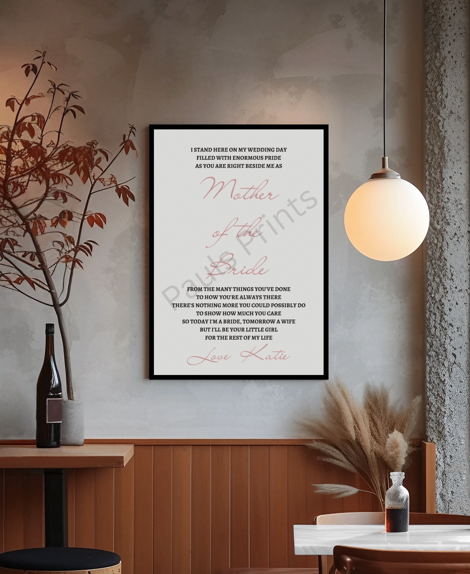 Mother of the Bride wedding day message in a black frame on a rustic wall above a wood bench and foliage.