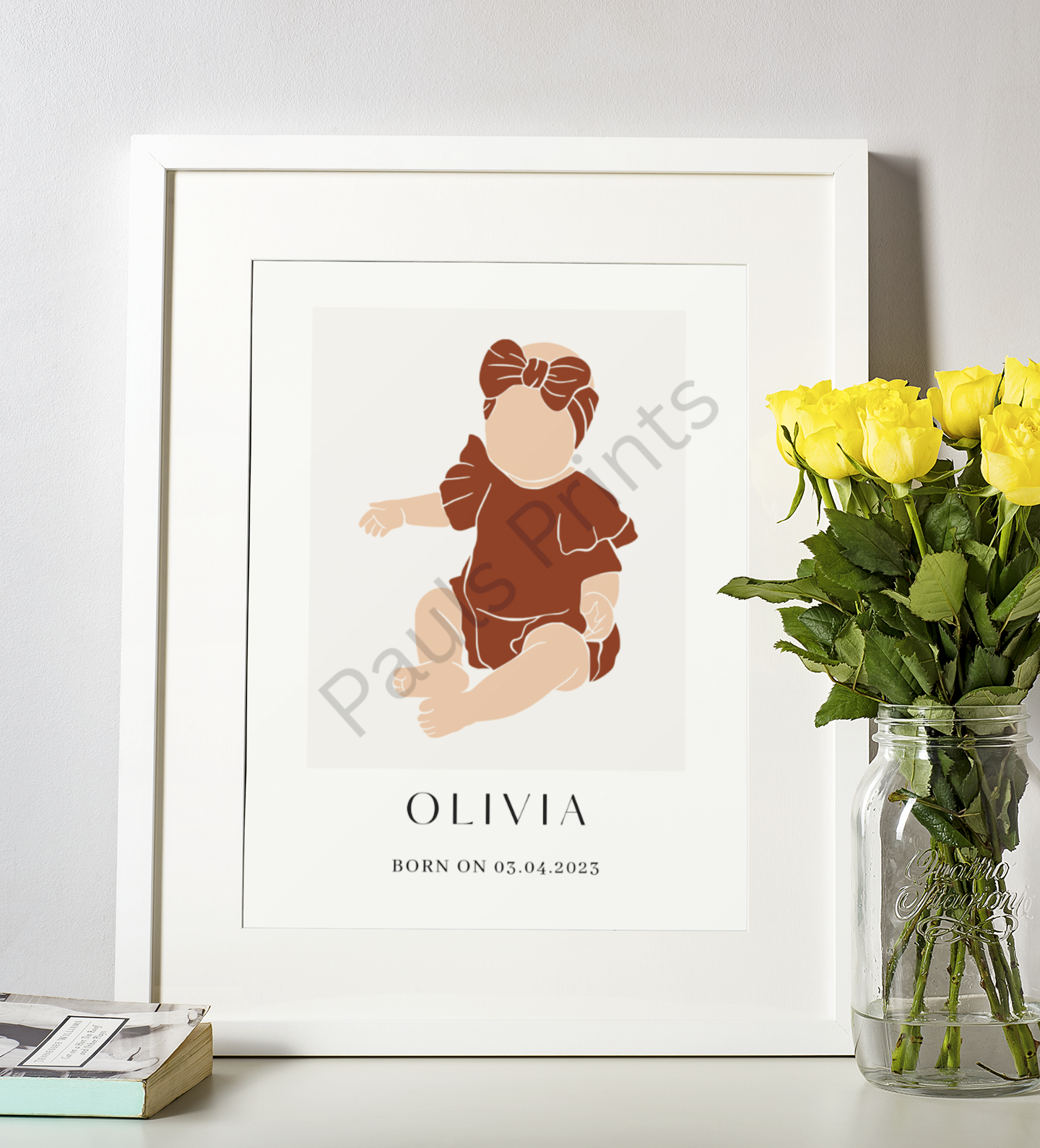 Framed personalised baby print with brown dress, styled on a shelf next to a glass jar of fresh yellow roses.