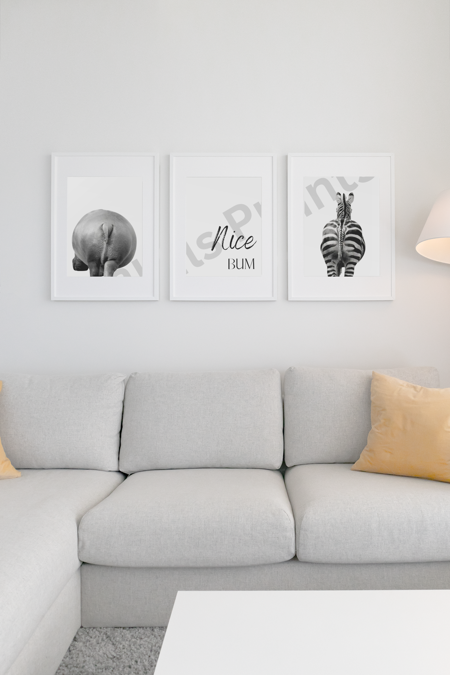 Modern, bright living room with a grey sectional sofa and a funny three-piece “Nice Bum” wall art featuring a hippo, zebra, and script quote.