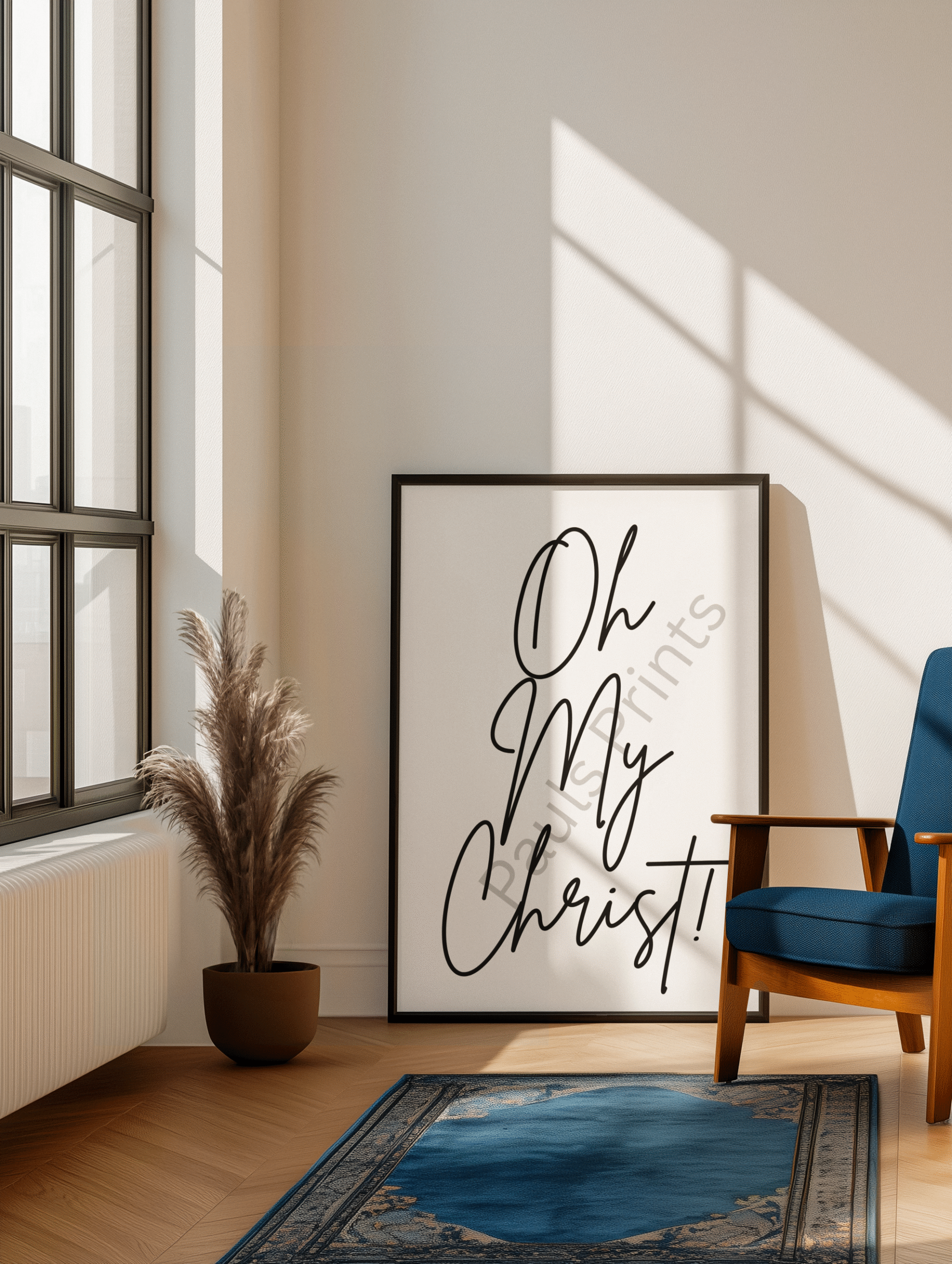 Oversized Oh My Christ framed print leaning against a wall beside a window, paired with a blue chair and indoor plant in a bright room.