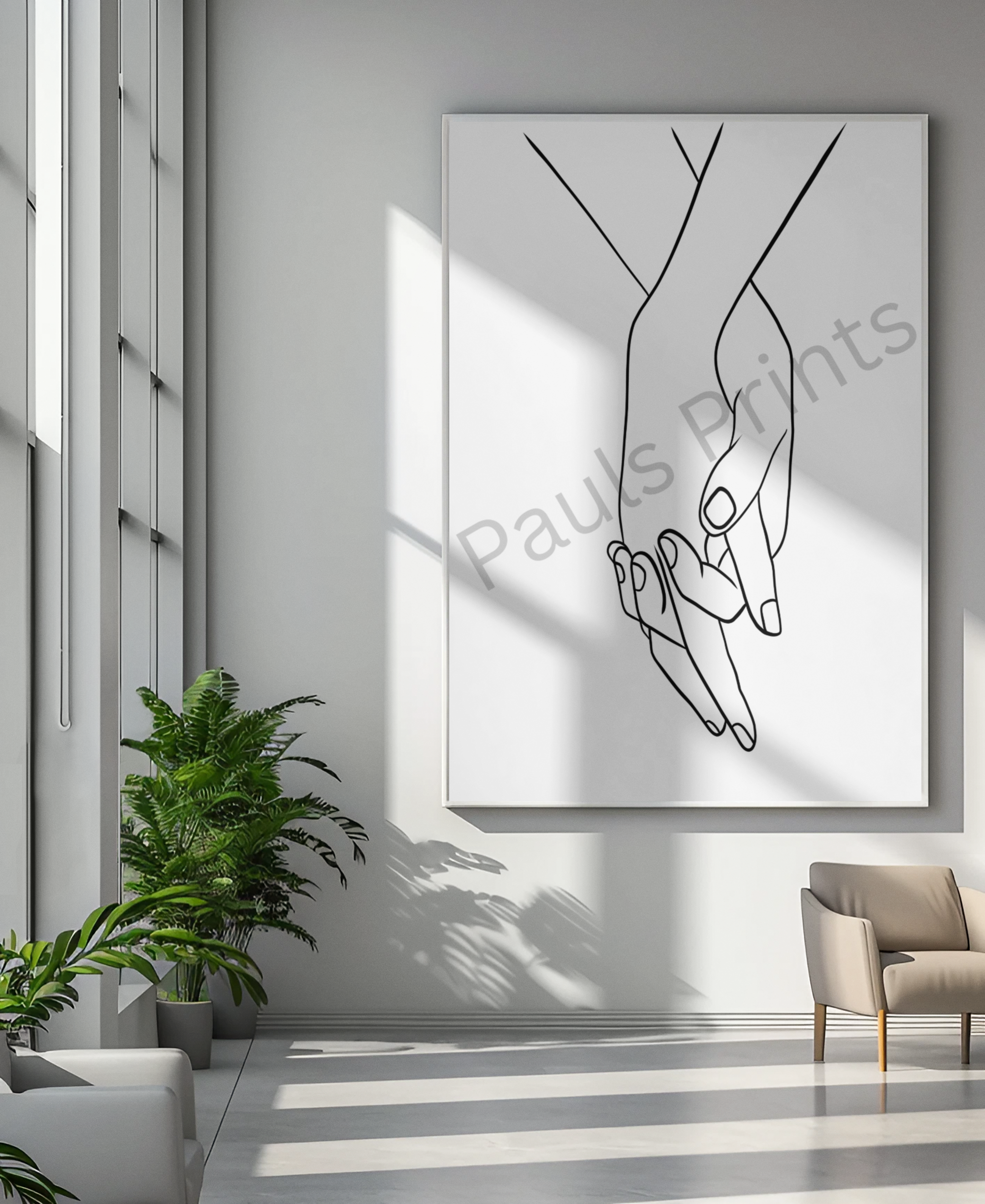 Extra-large framed holding hands print in a bright, modern atrium with tall windows and green potted plants.