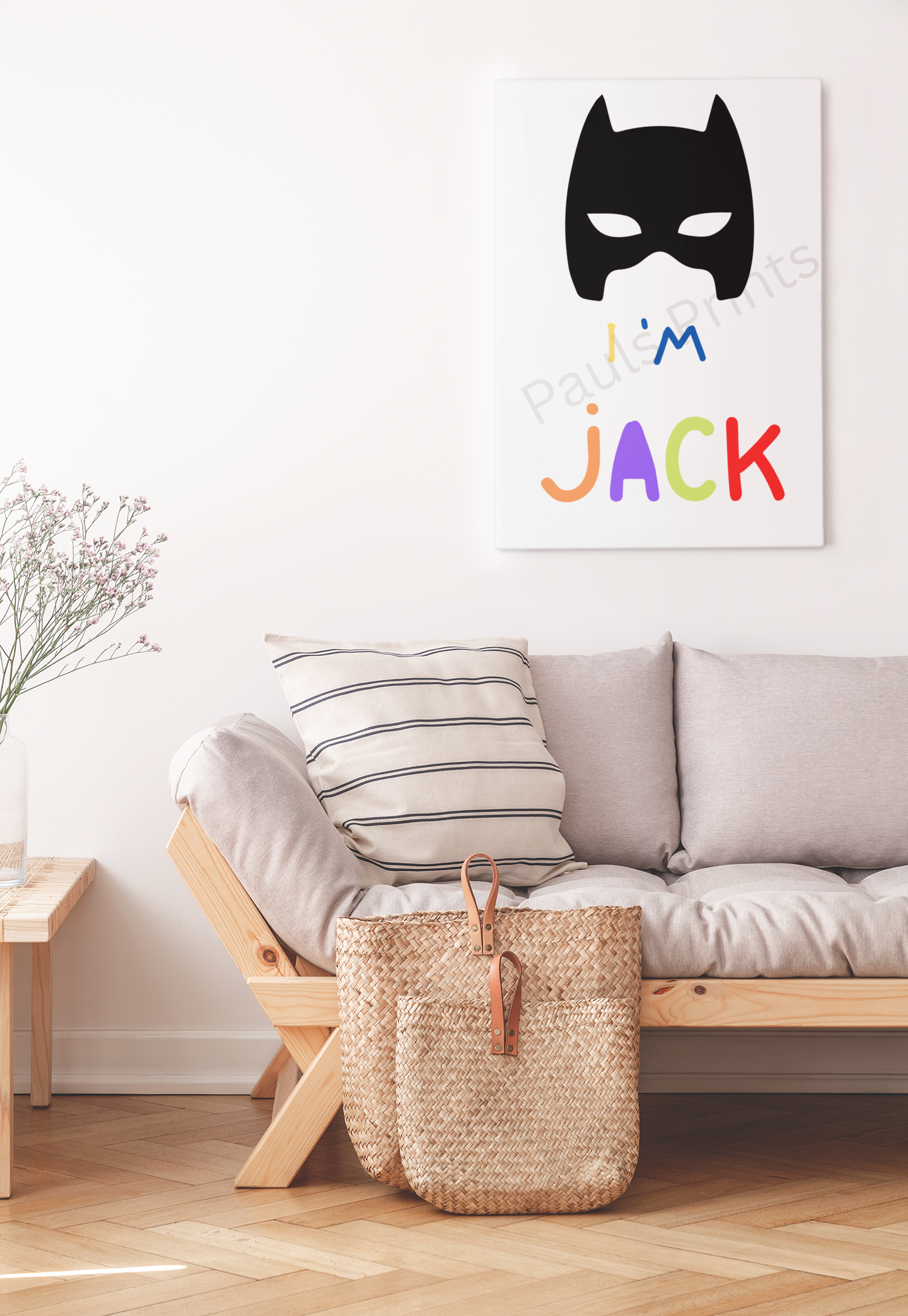 Canvas print featuring a Batman mask and “I’m Jack” in bright colours, hanging above a beige sofa with striped cushions.