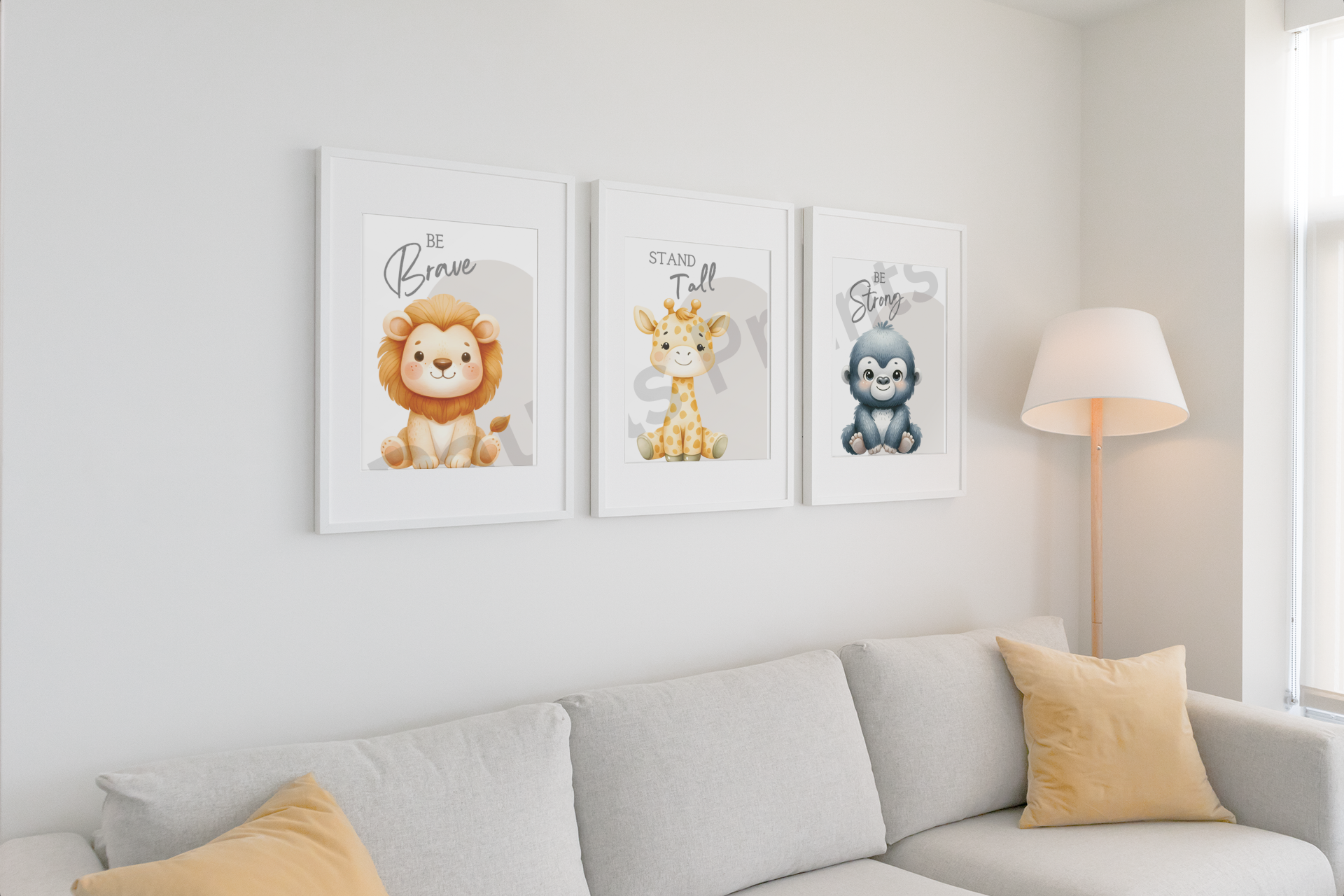 Three safari animal prints — lion with “Be Brave,” giraffe with “Stand Tall,” and gorilla with “Be Strong” — in white frames above a light grey sofa with neutral cushions and a floor lamp.