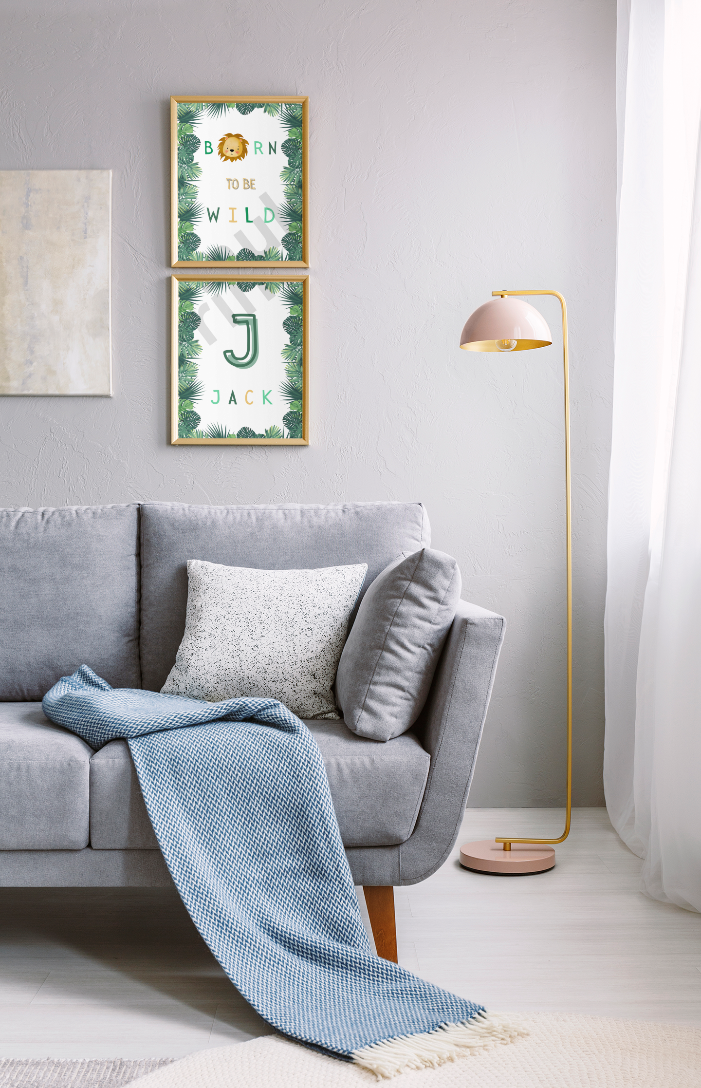 Stacked jungle-themed prints—“Born to be Wild” and “Jack”—hang vertically on a grey wall beside a plush sofa and gold standing lamp, adding character to a softly lit family space.