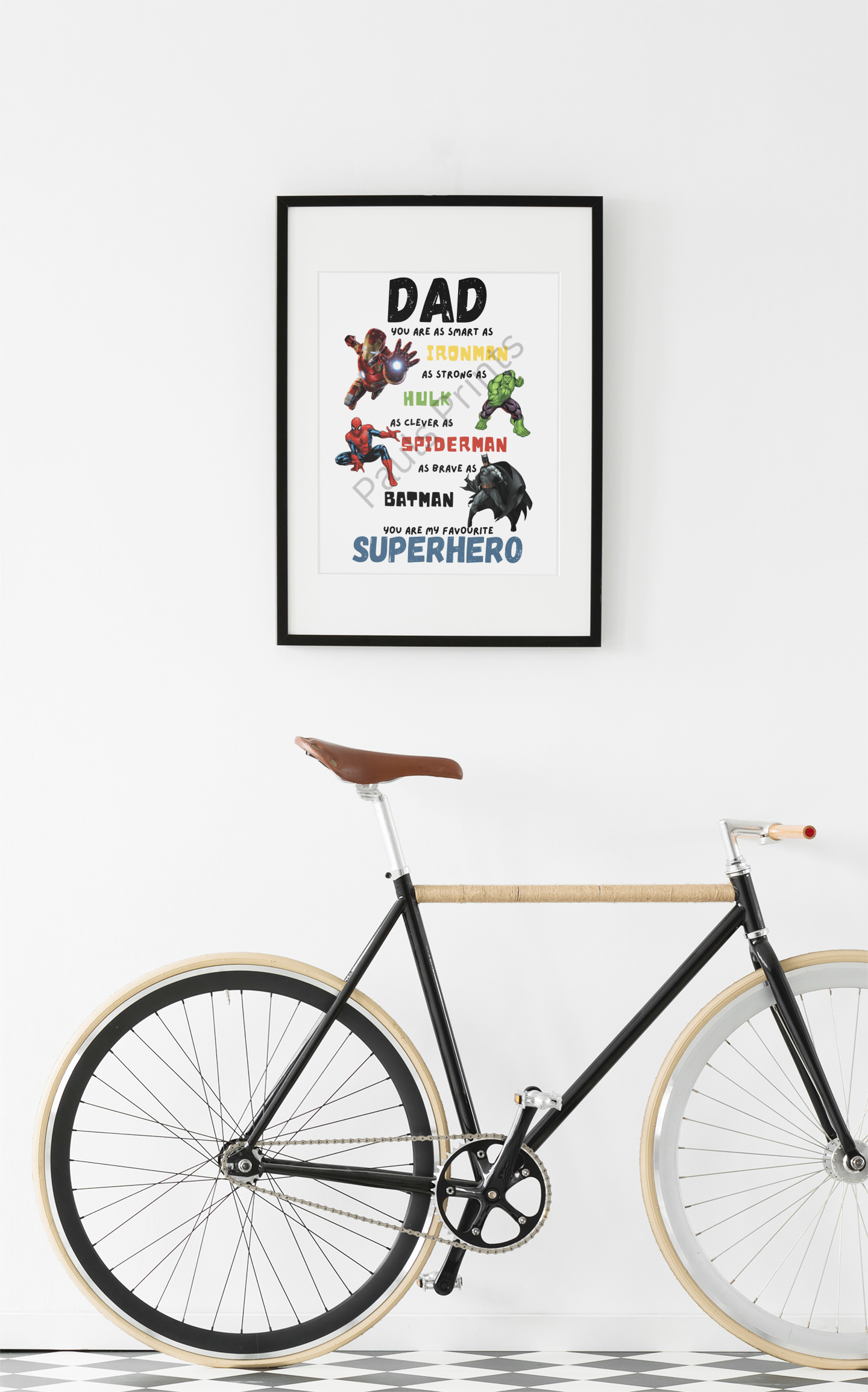Framed superhero dad quote featuring comic characters, hanging on white wall above a modern black bicycle.