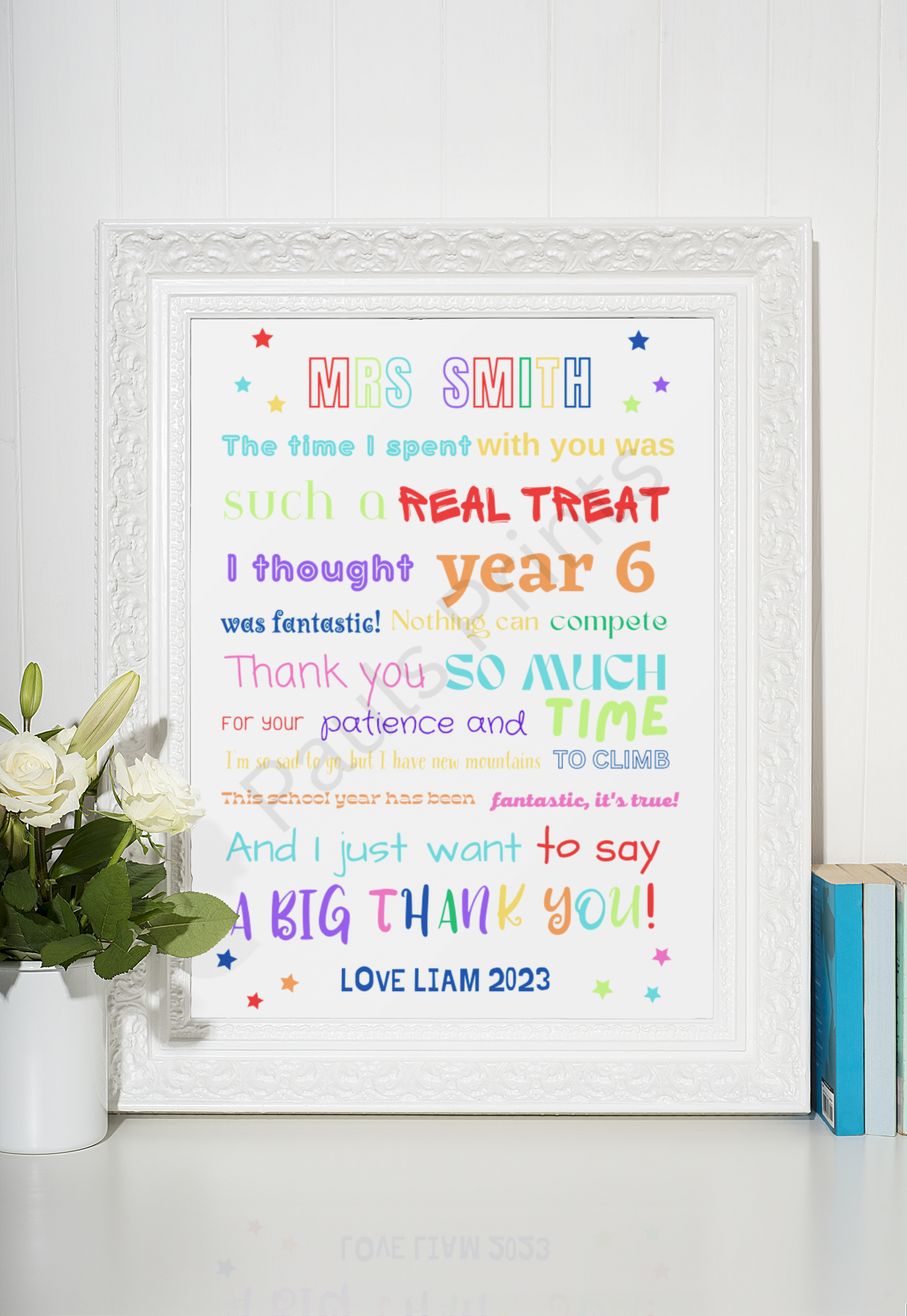 Rainbow-themed teacher thank you print in a white ornate frame, styled with white roses and books on a white background.