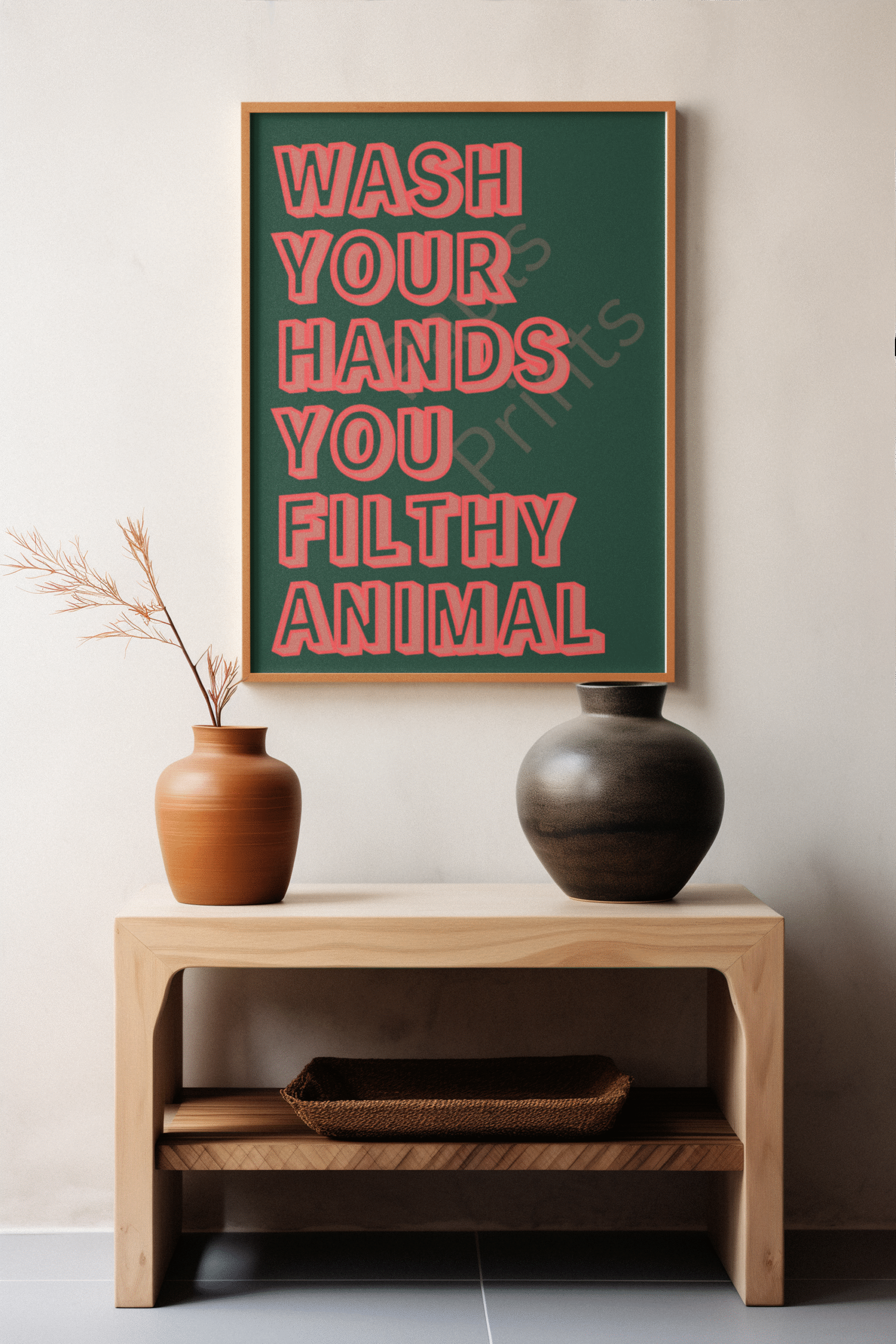 Fun typography wall art print with red outlined block letters on a green background reading “Wash Your Hands You Filthy Animal,” set against a black wall and marble tabletop.