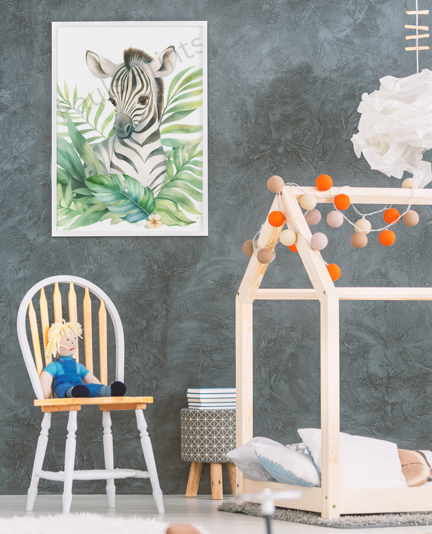 Charming watercolour zebra illustration surrounded by lush green tropical leaves, framed in white, hanging on a grey textured wall above a wooden kids’ chair with a doll.