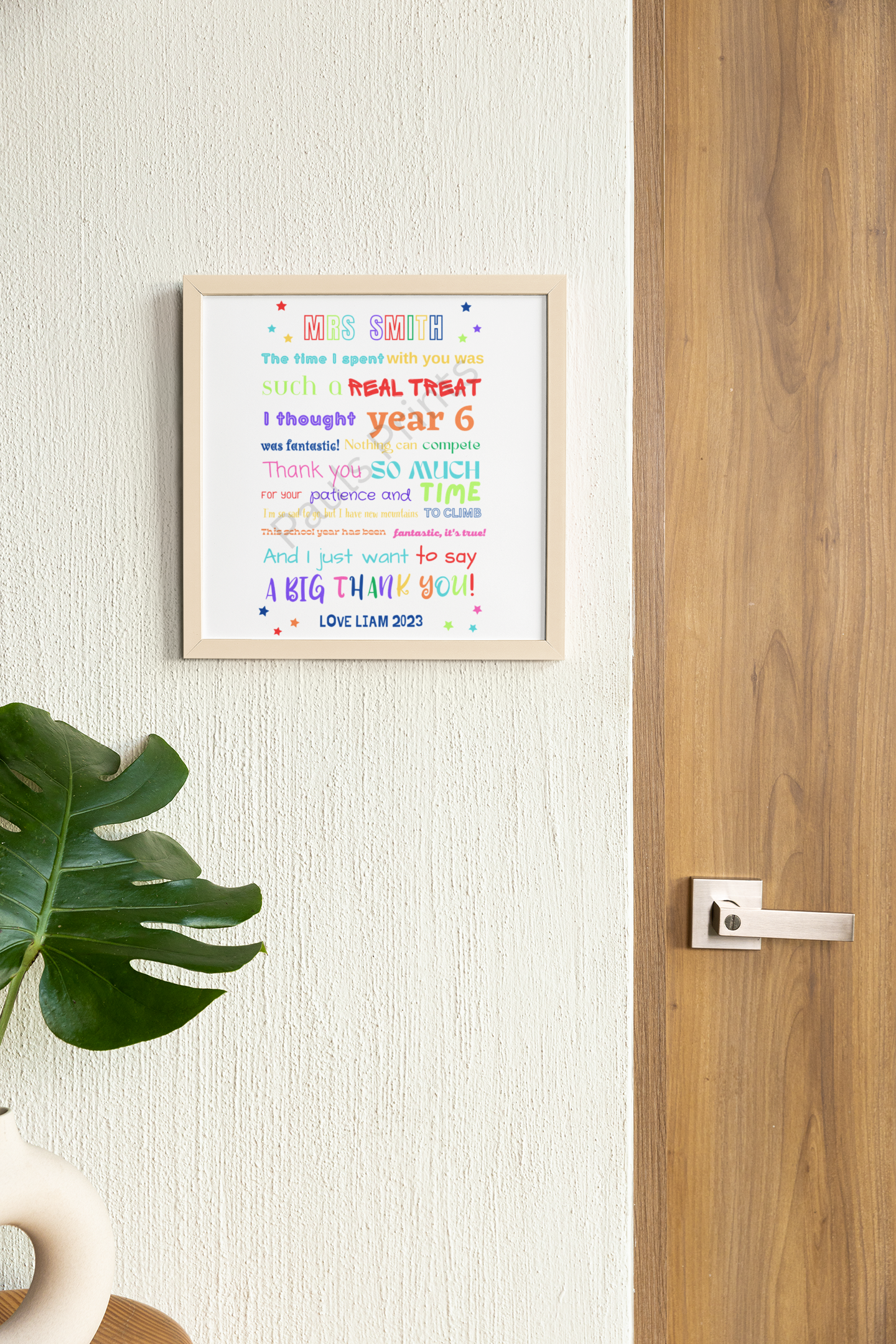 Vibrant end-of-year teacher thank you framed print hanging on cream wall near a wooden door with plant styling.