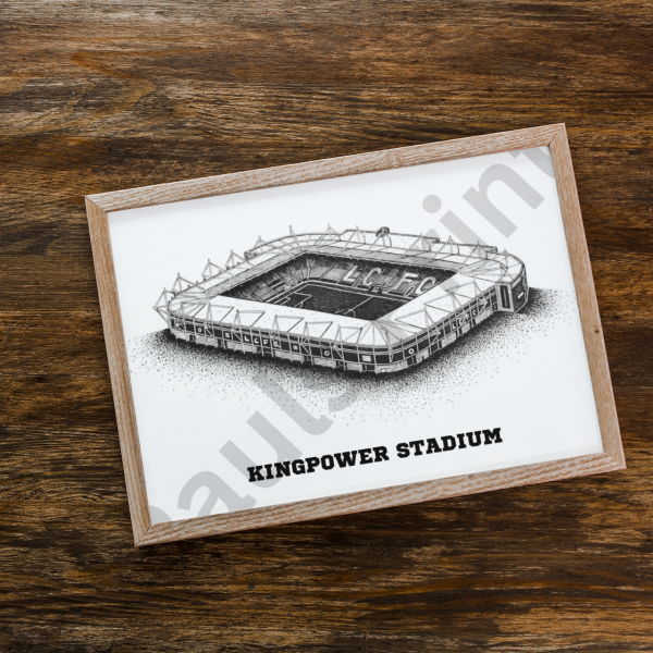 Flatlay of King Power Stadium sketch framed in natural oak on a dark rustic wood surface