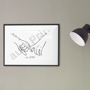 Small framed line art of Matt and Sarah holding hands with est. 2016 text, displayed on a white coffee table next to a potted plant and sofa